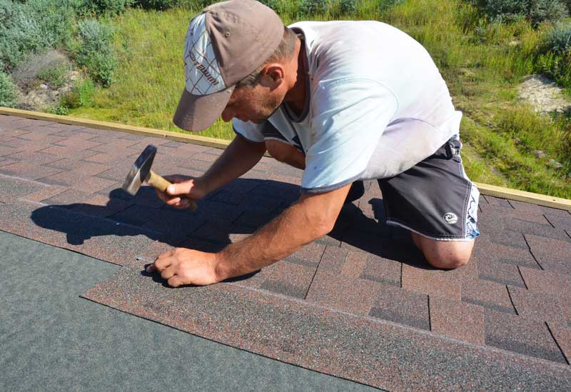 a roofing contractor nails down asphalt shingles