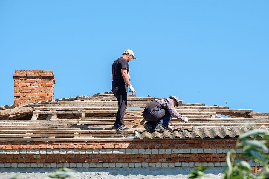 Two man performing emergency repairs to a damaged roof