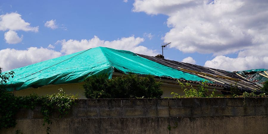 A tarp lays over a damaged rood