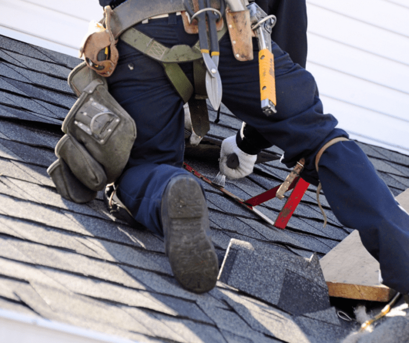 Contractor kneeling on roof, repairing shingles