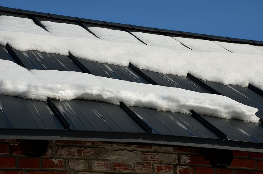 A galvanized metal roof partially covered in snow, illustrating the durability and weather resistance of new roofs in Ohio. When considering the cost of a new roof, factors like material type and climate conditions affect the average cost of a new roof in Ohio.