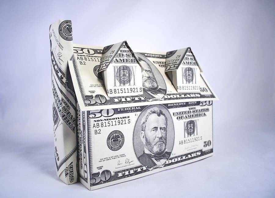 House made of money, symbolizing the factors that influence the cost to replace a roof, including roofing materials, labor, and insurance expenses.