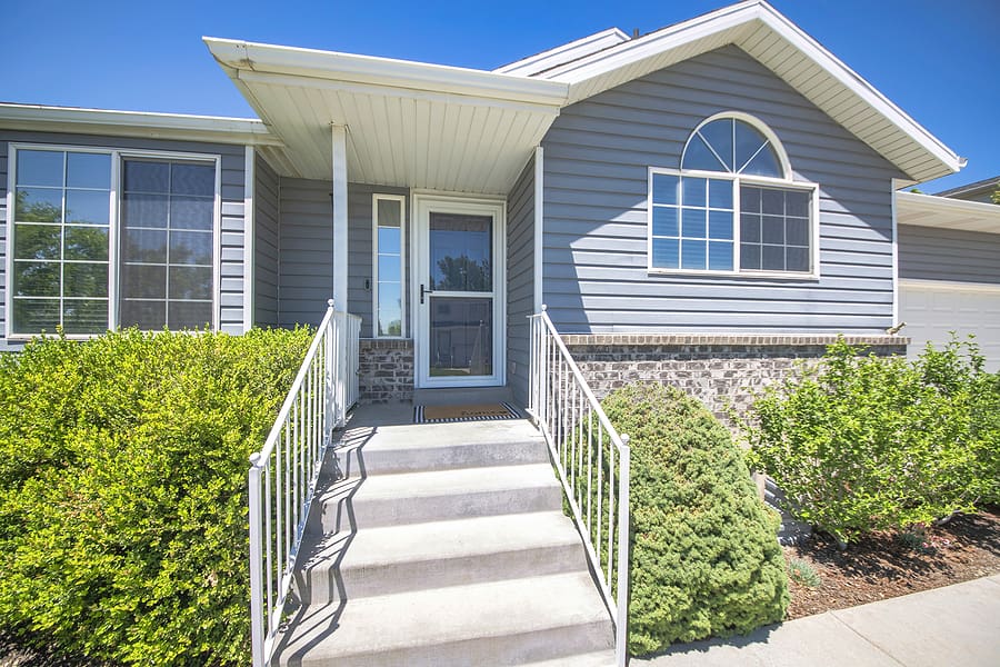 Front entrance of a home with newly installed durable siding by Wagner, featuring a blend of brick and smooth gray vinyl panels. The fresh siding adds to the home’s curb appeal and provides a resilient barrier against the elements, highlighting Wagner’s expertise in siding replacement and installation with quality materials like vinyl and options from brands like Mastic by Ply Gem.