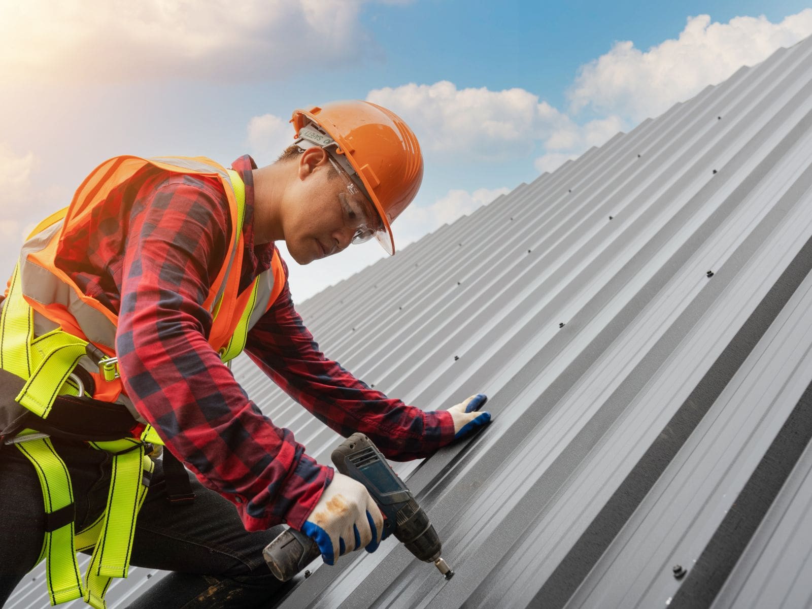 Roofing contractor installing metal roofing panels with power drill during professional roof installation by Wagner Roofing